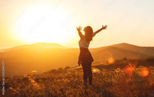 Happy woman jumping and enjoying life  at sunset in mountains.