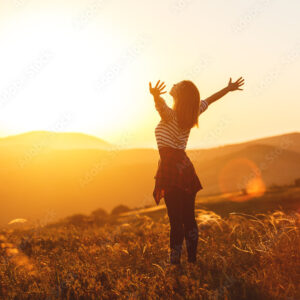 Happy woman jumping and enjoying life at sunset in mountains.